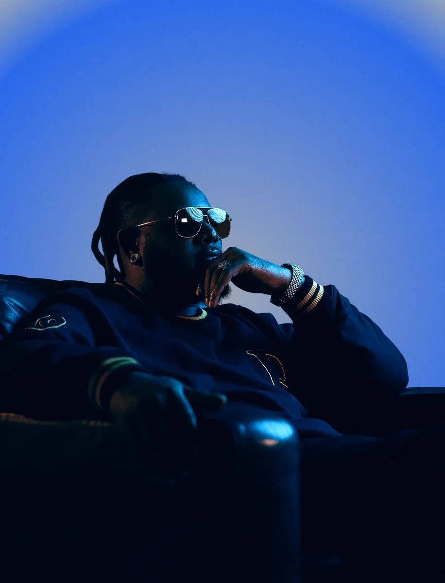 Portrait of T-Pain in an armchair against a blue background
